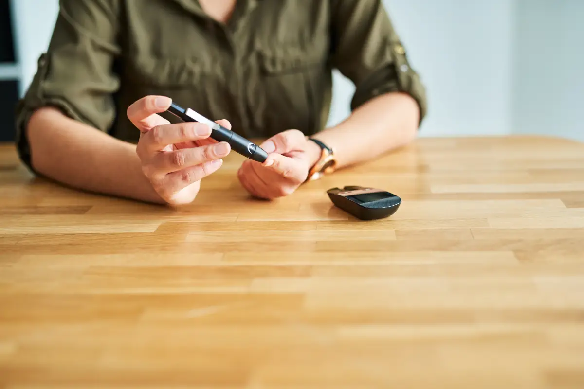 Person using a glucose meter to check blood sugar levels, showing diabetes as one of the diseases that cause cataracts