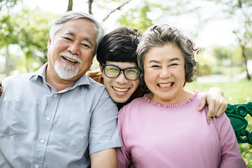 Smiling multi-generational Asian family outdoors after follow up after cataract surgery and vision recovery.