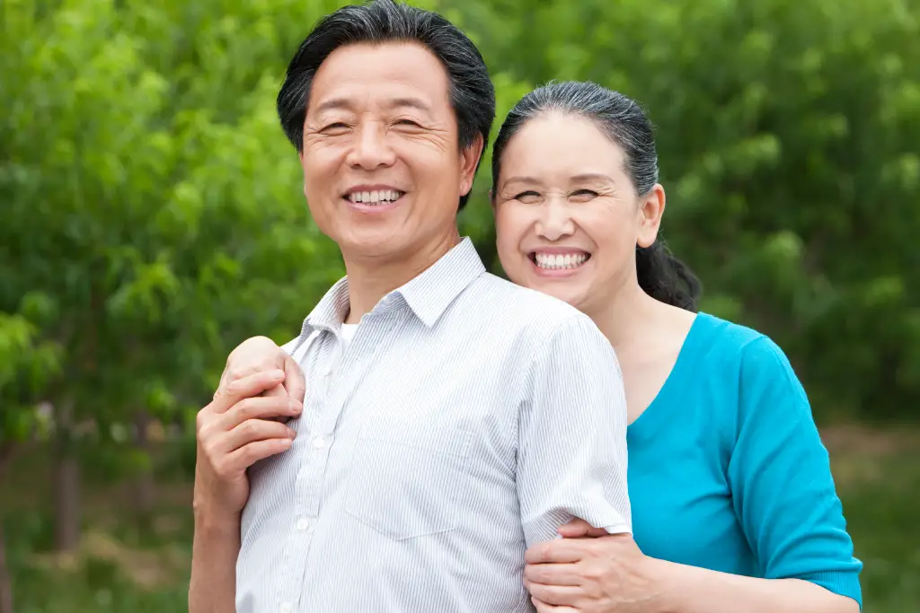 Smiling older Asian couple outdoors, representing healthy vision and recovery after cataract surgery.