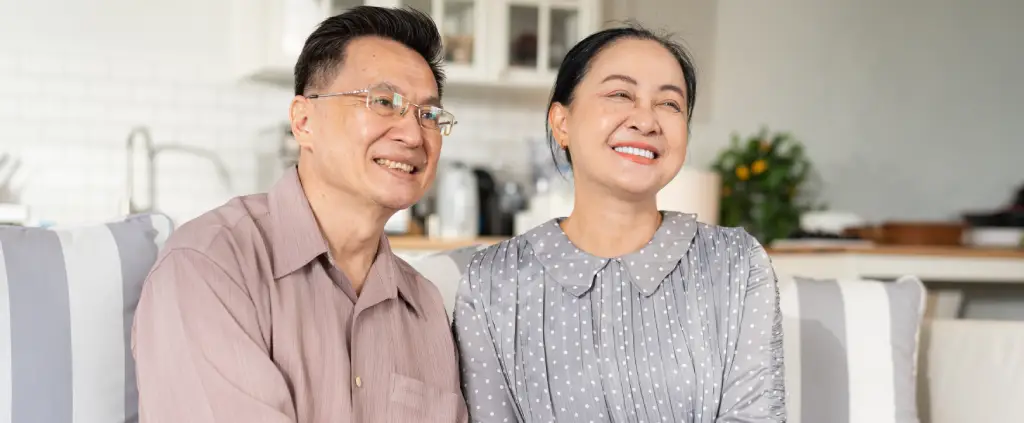 Older Asian couple smiling at home after follow up after cataract surgery and vision recovery.