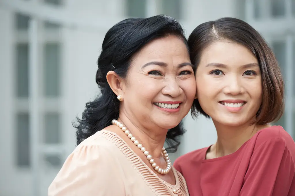 Asian mother and daughter smiling together, representing healthy ageing and awareness of diseases that cause cataracts.